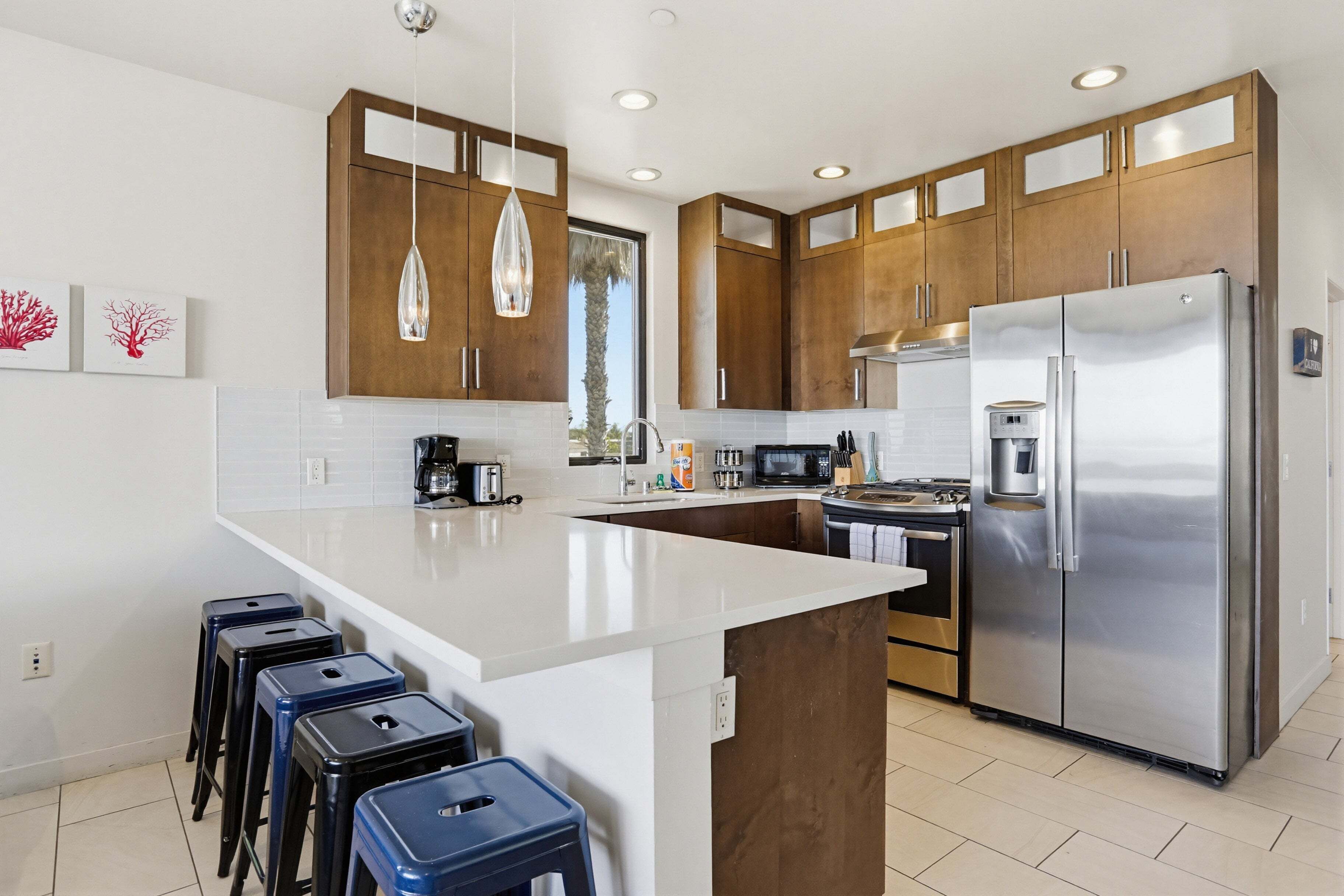 A modern kitchen with wooden cabinets, stainless steel appliances, and a central island with stools.
