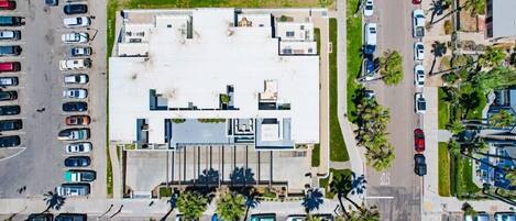 An aerial view of a parking lot adjacent to a building with multiple floors and a flat roof.