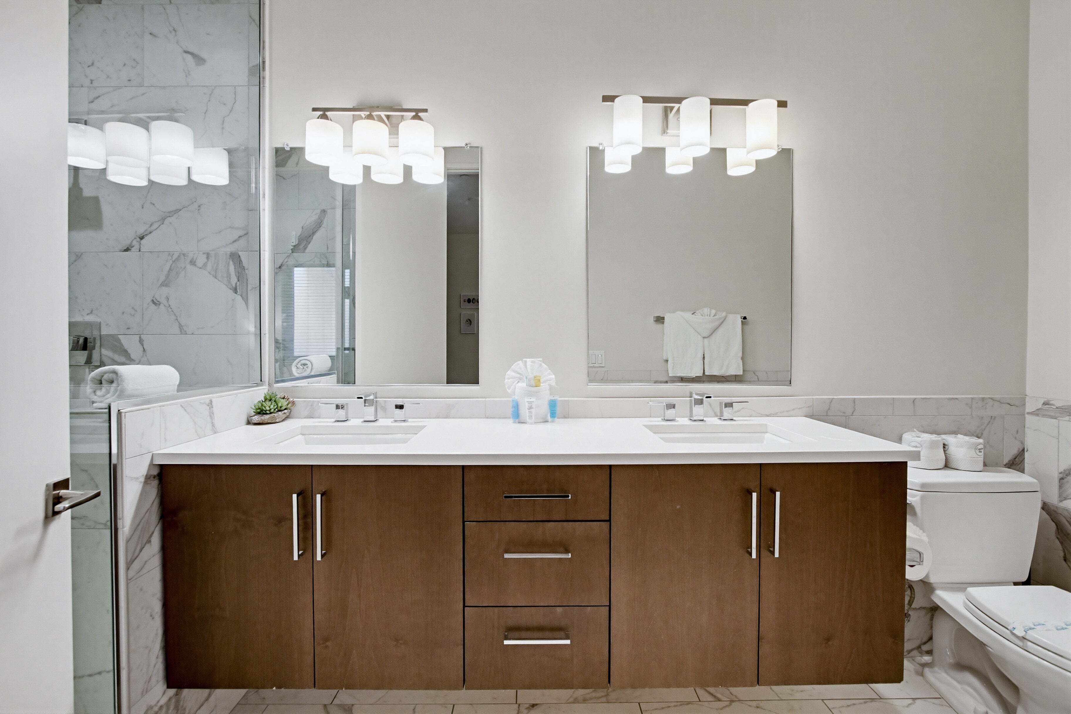 Un bagno moderno con un ampio mobile lavabo, due lavandini e un grande specchio.
