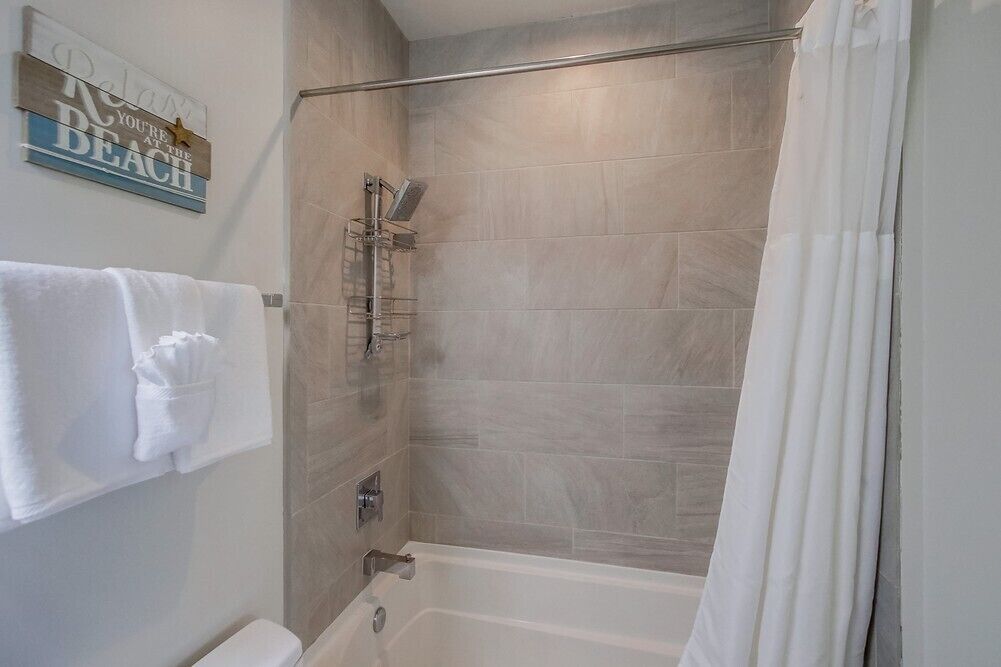 A bathroom with a bathtub, a glass shower enclosure, and a towel rack with towels.