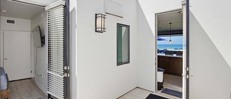 A modern interior with a sliding door leading to a balcony, a small window, and a visible kitchen area.
