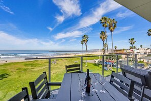 A balcony with a table set for dining, overlooking a beach and ocean. - Ocean Park 08 (San Diego)