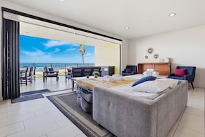 Una habitación de hotel moderna con balcón, una cama, zona de estar y vistas al océano.