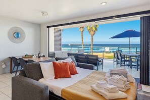 A modern hotel room with a bed, seating area, and a view of the ocean.