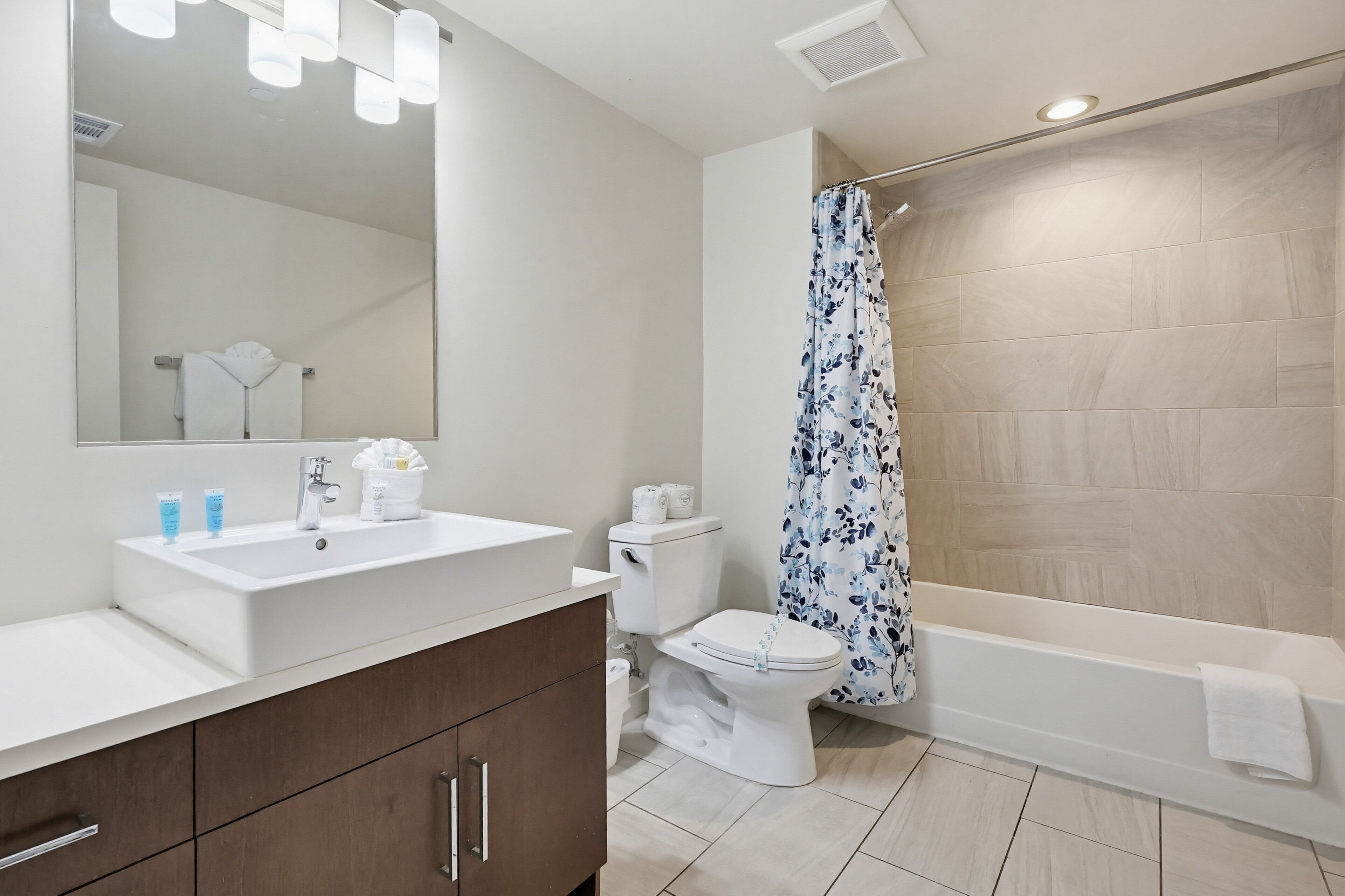 A bathroom with a white sink, mirror, toilet, and bathtub.