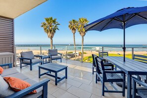 A terrace with outdoor seating, palm trees, and a view of the beach. - Ocean Park 09 (San Diego)