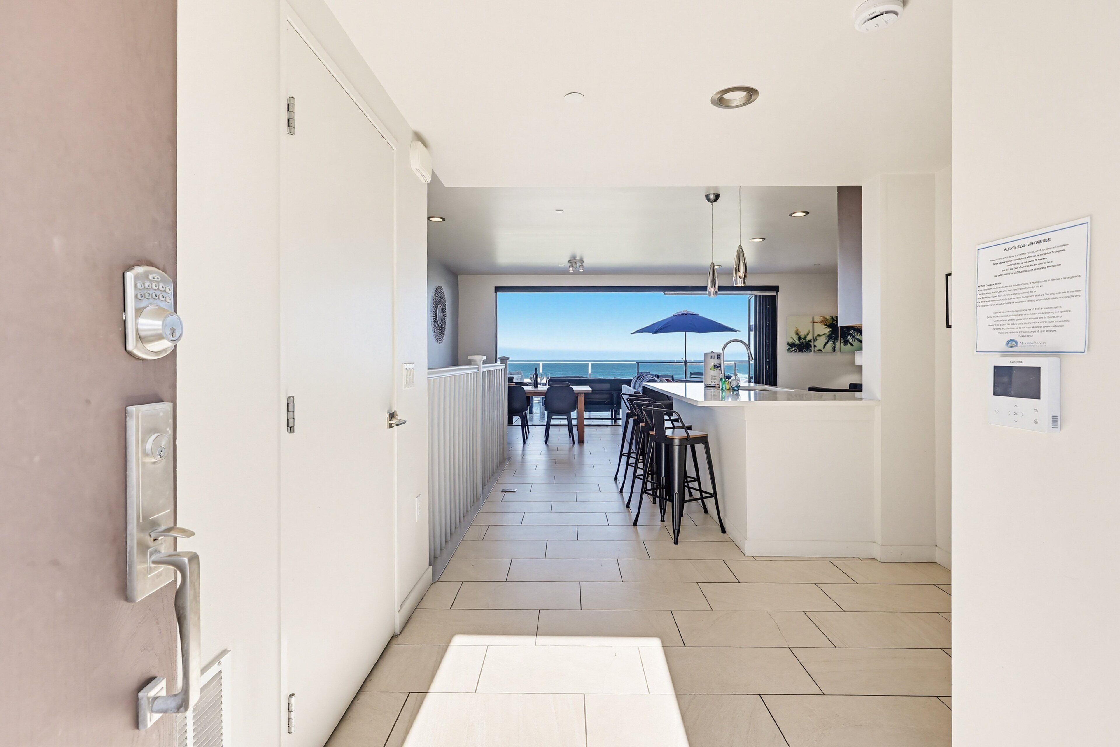 A modern kitchen with a view of the sea, a bar area, and a dining space.