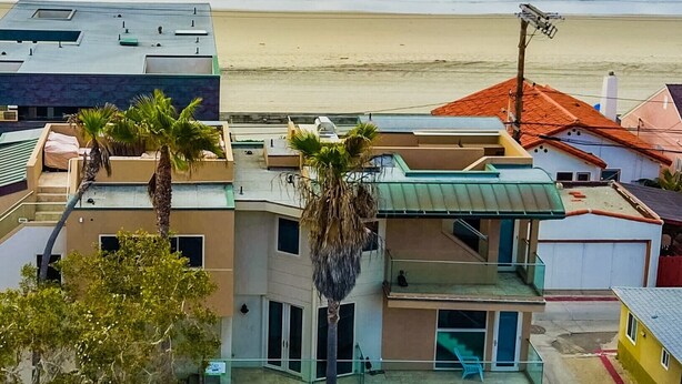 A coastal residential area with a multi-story building featuring balconies, a beach in the background, and palm trees. - Ocean View Luxury 2 (San Diego)