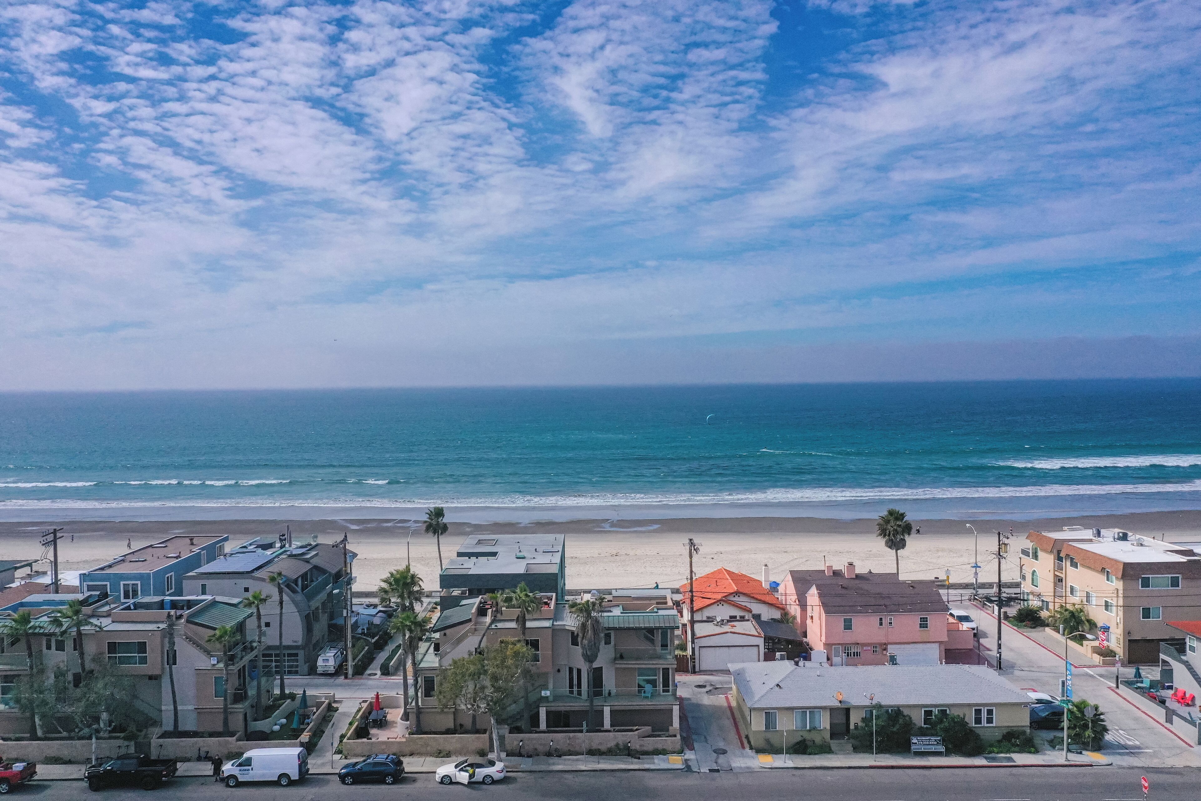 A coastal town with buildings along the beachfront, a clear sky, and the ocean in the background.