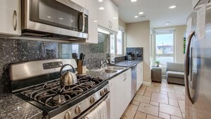 A modern kitchen with stainless steel appliances, granite countertops, and a view to the living area. - Ocean View Luxury 2 (San Diego)