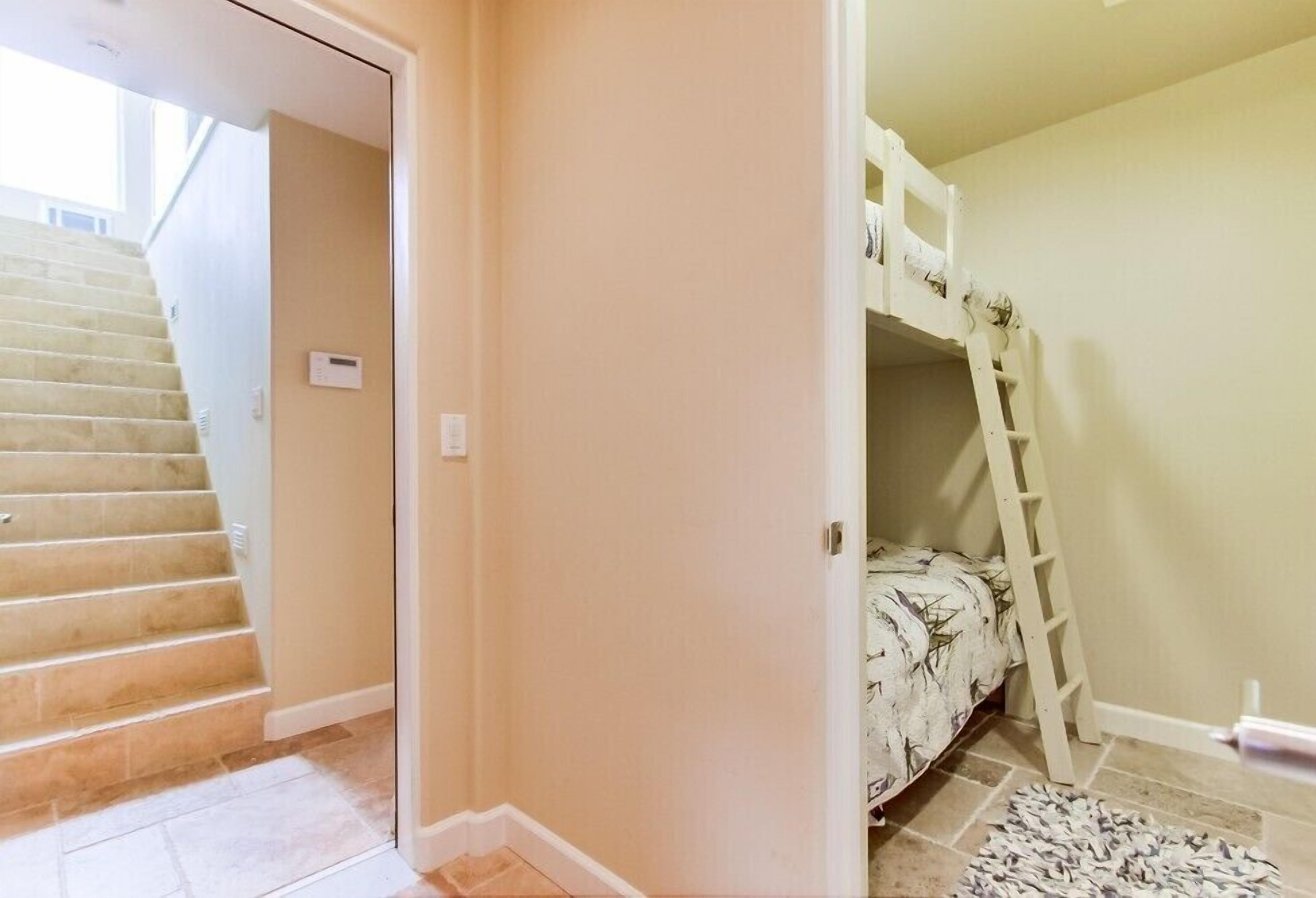 Un dormitorio con literas, una escalera y una alfombra pequeña.