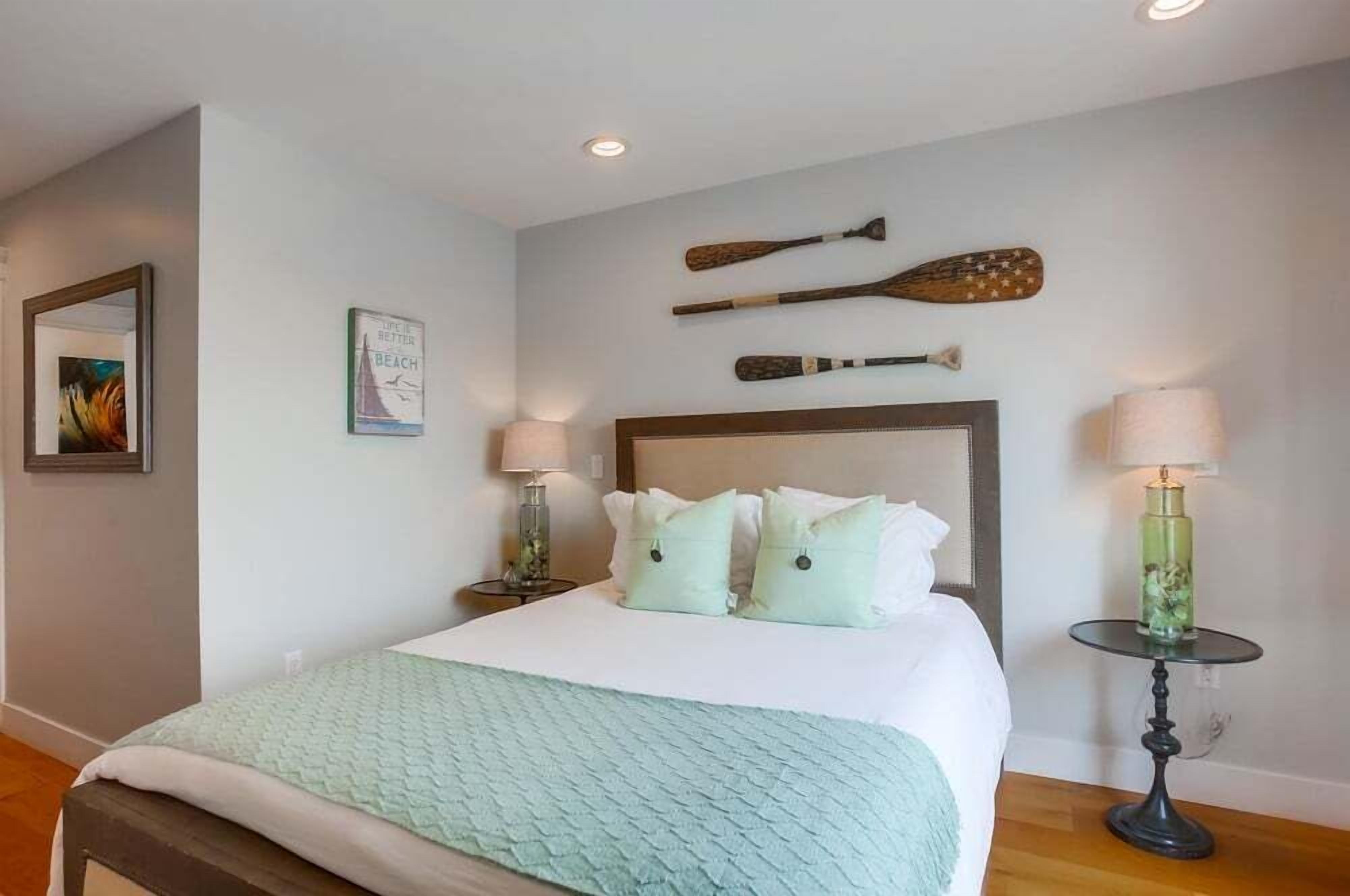A neatly arranged bedroom with a bed, two bedside tables with lamps, and wall-mounted sports equipment.