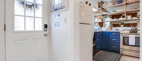 A kitchen with white cabinets, a refrigerator, a stove, and a sink.