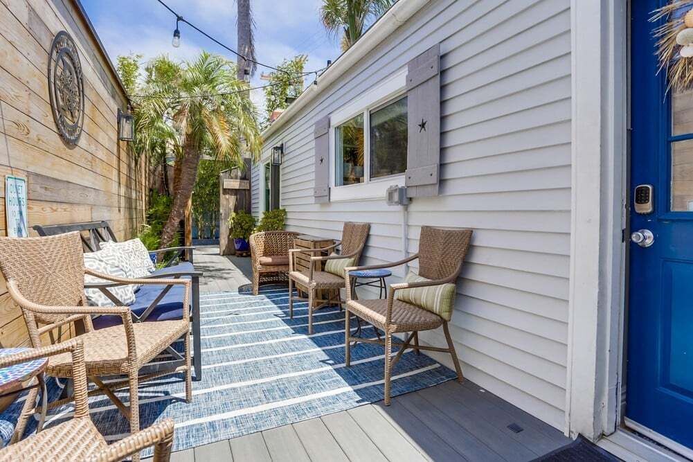 Un espace patio aménagé avec des meubles en osier et un tapis à rayures bleues et blanches.