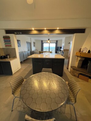 Una cucina moderna con isola centrale, mobili scuri e zona pranzo con tavolo rotondo e sedie imbottite.