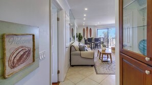 A modern interior with a sofa, dining table, and chairs, a 'Welcome' sign, and a view to the outside. - See the Sea 52 (San Diego)