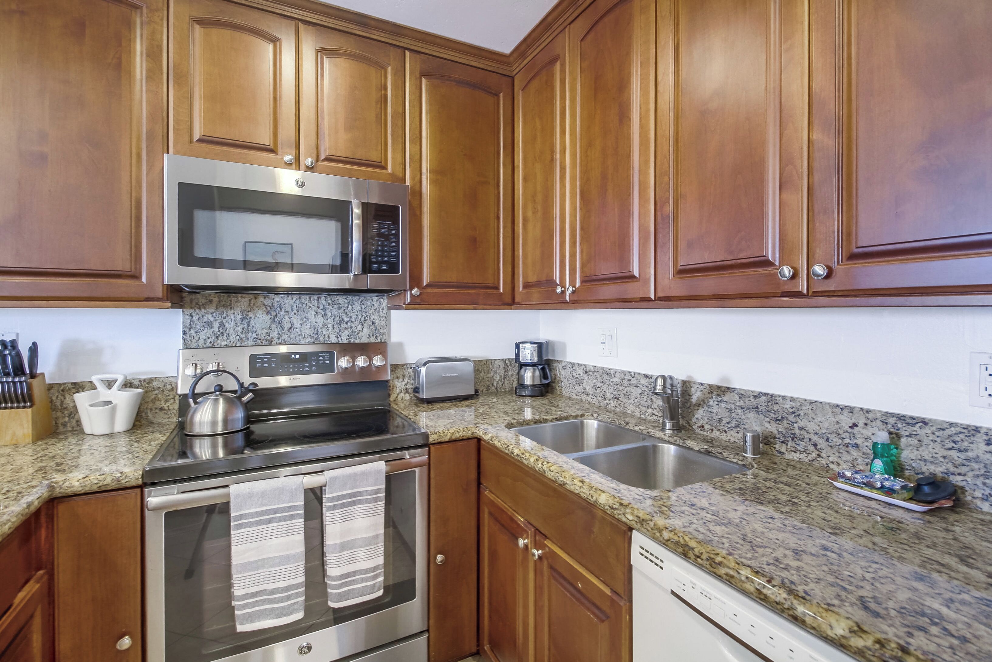 A kitchen with wooden cabinets, stainless steel appliances, granite countertops, and a double sink.