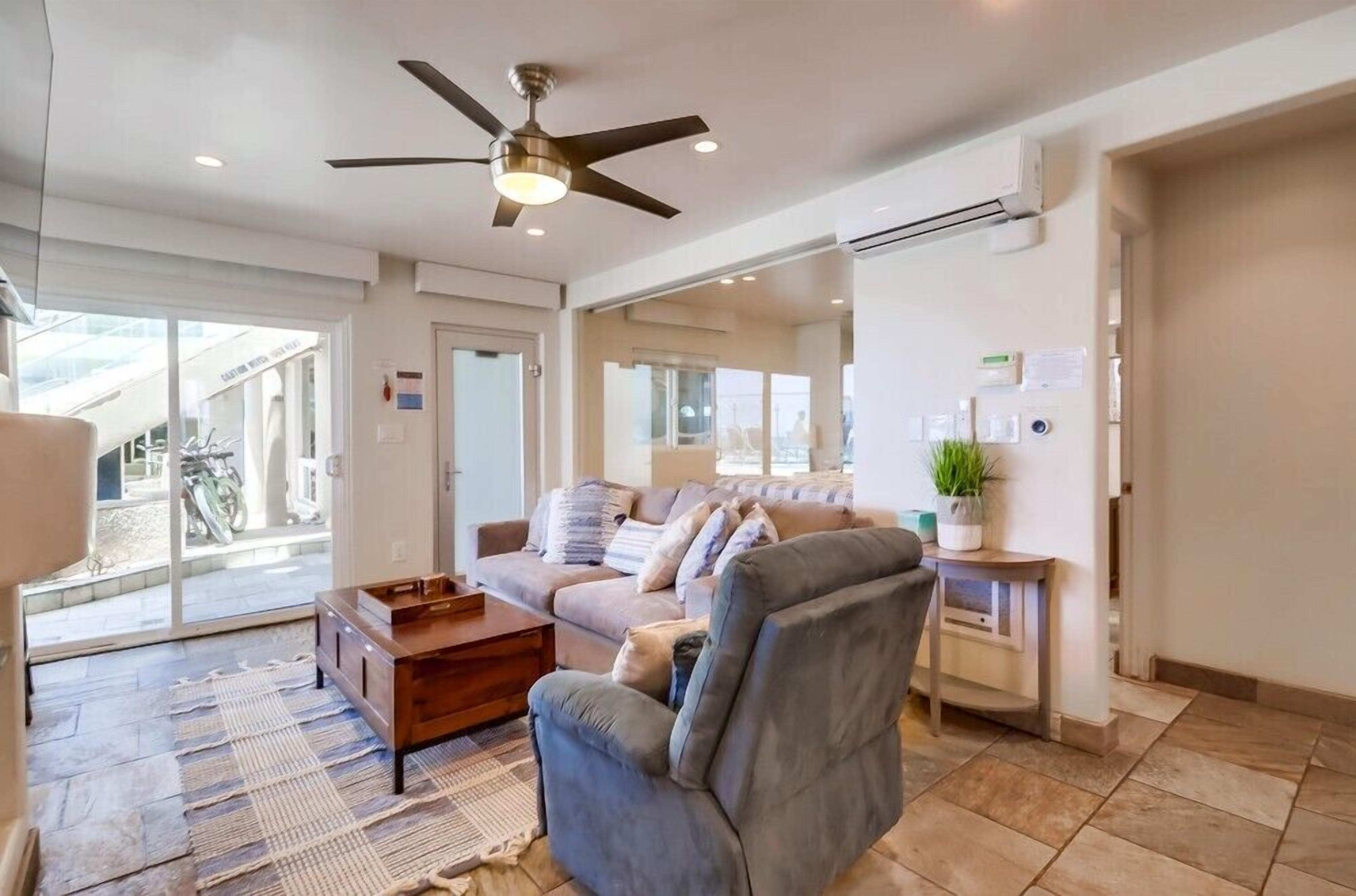 A modern living room with a ceiling fan, a sofa, a coffee table, and a small side table with a plant.