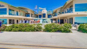 A modern hotel with a central atrium, multiple balconies, and a clear sky. - Surf Rider D (San Diego)