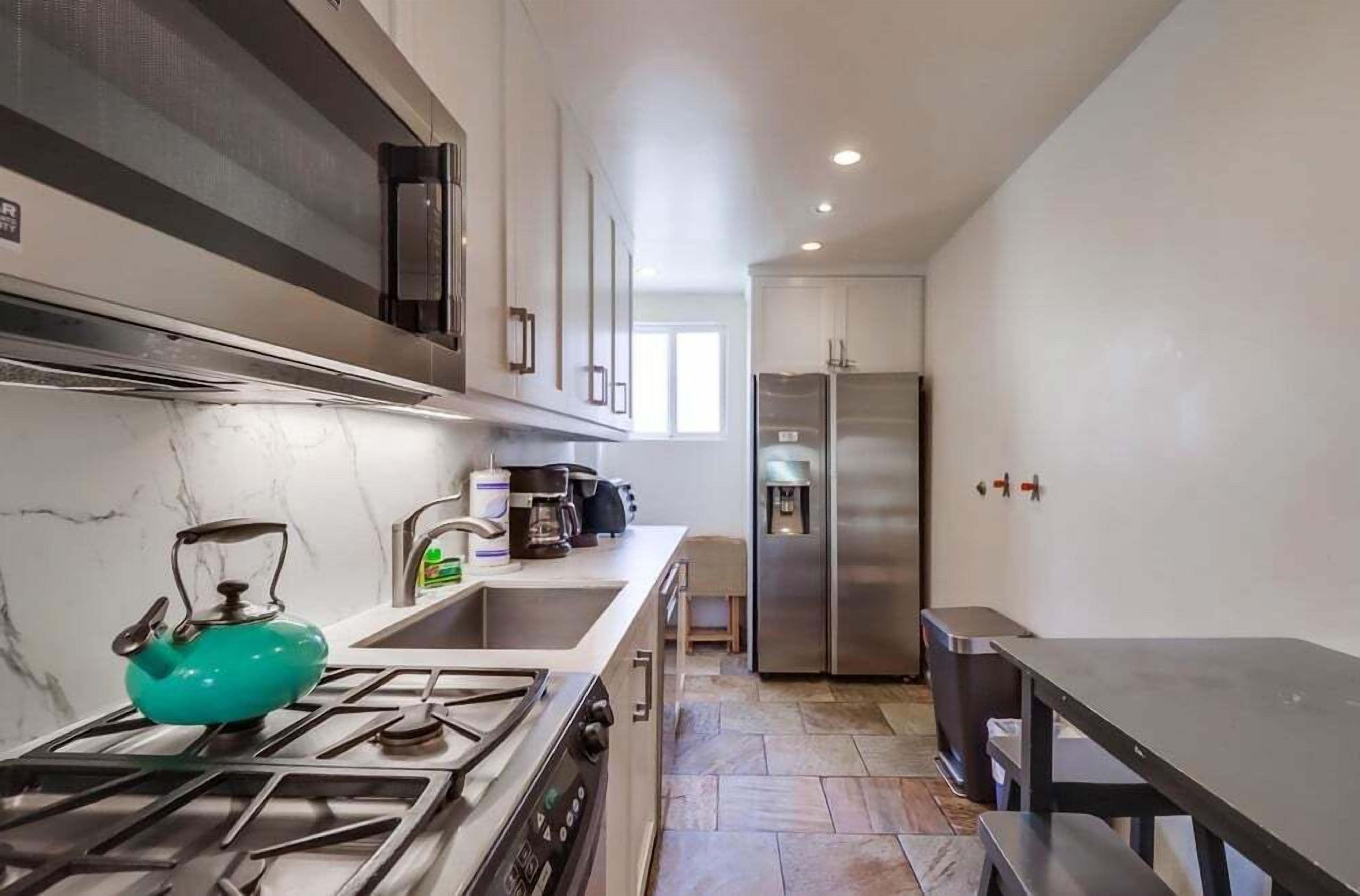Una cocina moderna equipada con estufa a gas, hervidor, cafetera y refrigerador.