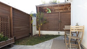 En træterrasse med et mønstret tæppe, en træbænk og et lille bord.