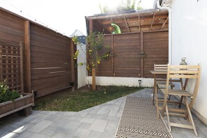 Un patio in legno con un tappeto decorato, una panca di legno e un tavolino.