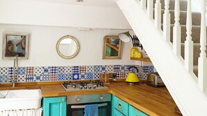 Une cuisine avec des armoires de couleur turquoise, un plan de travail en bois, une cuisinière et un évier.