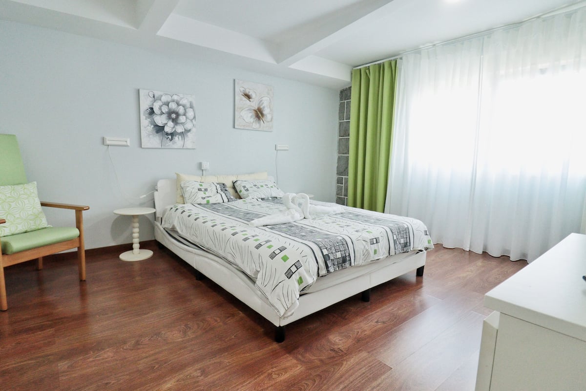 Un dormitorio con cama, una silla, una mesita de noche y obras de arte en la pared.