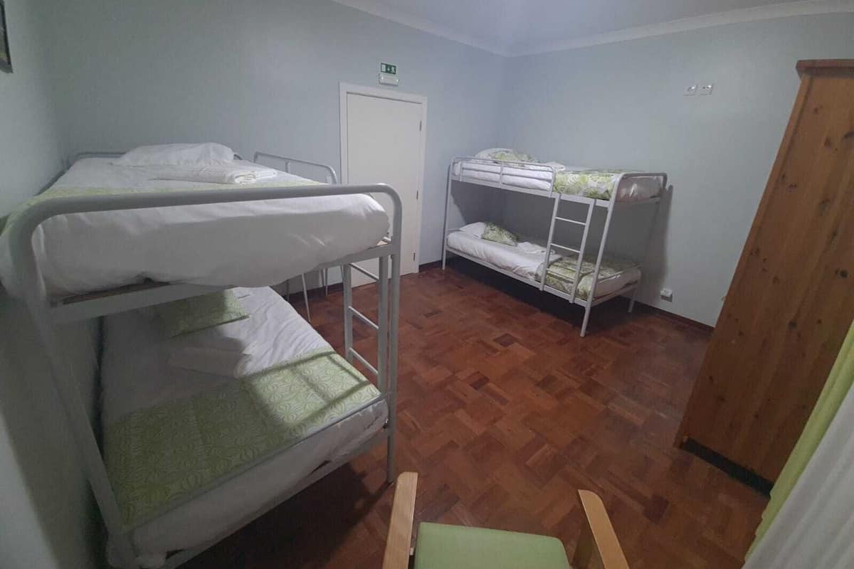 Un dormitorio con literas, un armario de madera y una puerta blanca con señal de salida de emergencia.