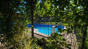 Una piscina al aire libre, sillones reclinables de piscina
