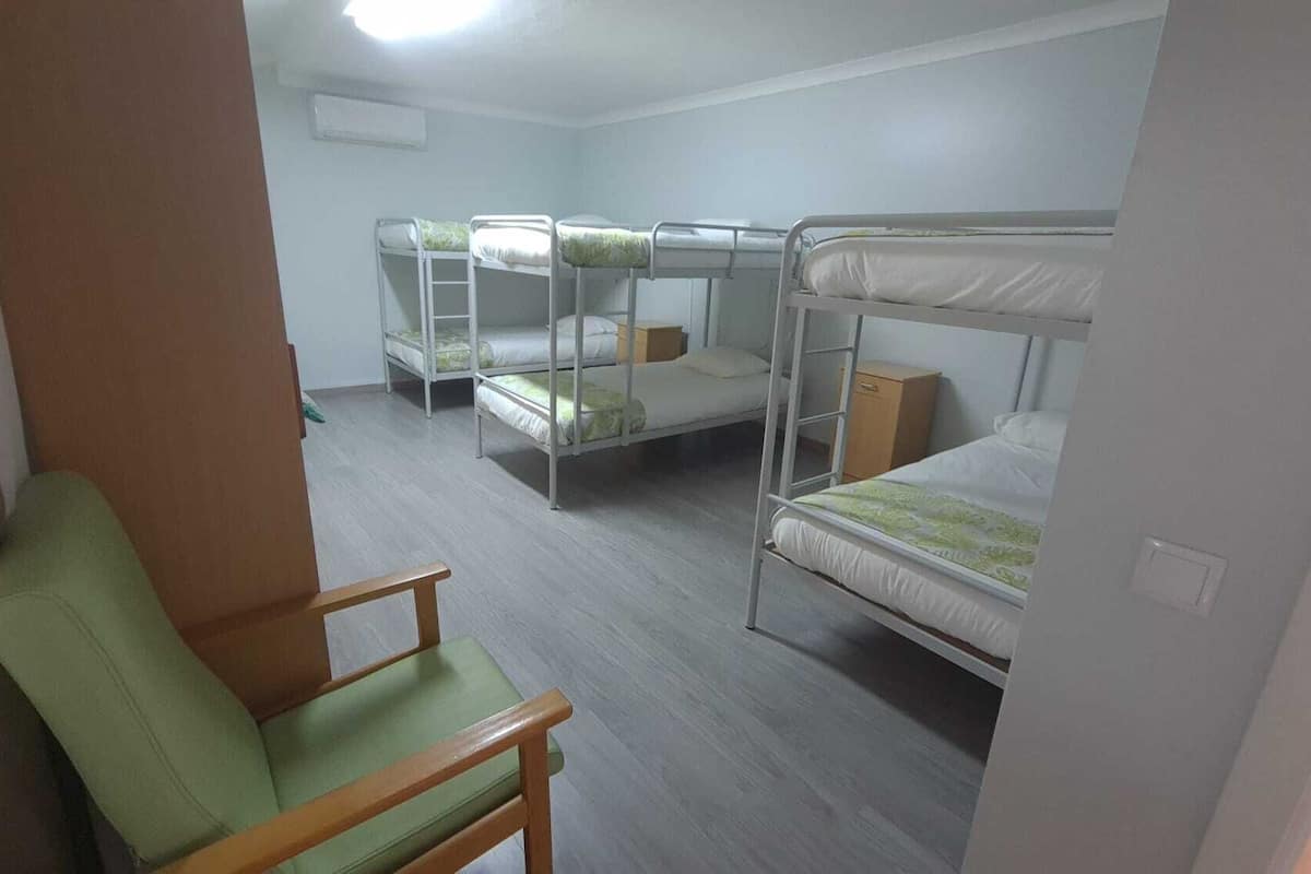 Un dormitorio con literas, una silla de madera y un armario pequeño.