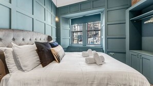 Een slaapkamer met een groot bed, een raam met uitzicht op de straat en een inbouwkast.