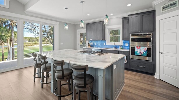 A modern kitchen with a large island, dark cabinetry, stainless steel appliances, and a view of a golf course. - Brand New, Golf Cart Included - 546 Remora Dr. (Fripp Island)