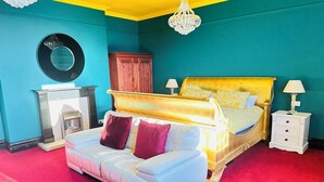 A bedroom with a large bed, a white sofa, a wooden cabinet, and a chandelier. - PHOENIX Apartments (Goole)