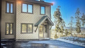Une maison à deux étages, dotée d’un toit en pente, de grandes fenêtres et d’un porche à l’avant.