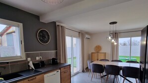 A modern kitchen with a dishwasher, a clock, and a dining area with a table and chairs.