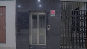Een lift met een digitaal scherm, een veiligheidsbord voor brand en een metalen poort.