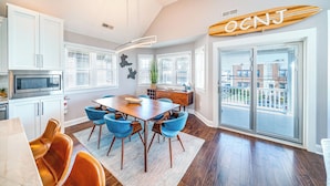 A modern kitchen with white cabinets, a built-in oven, and a wooden dining table with blue chairs. - Ocean City Beach Block: 5BR/4BA with Full Linen Service- Perfect for Family! (Ocean City)