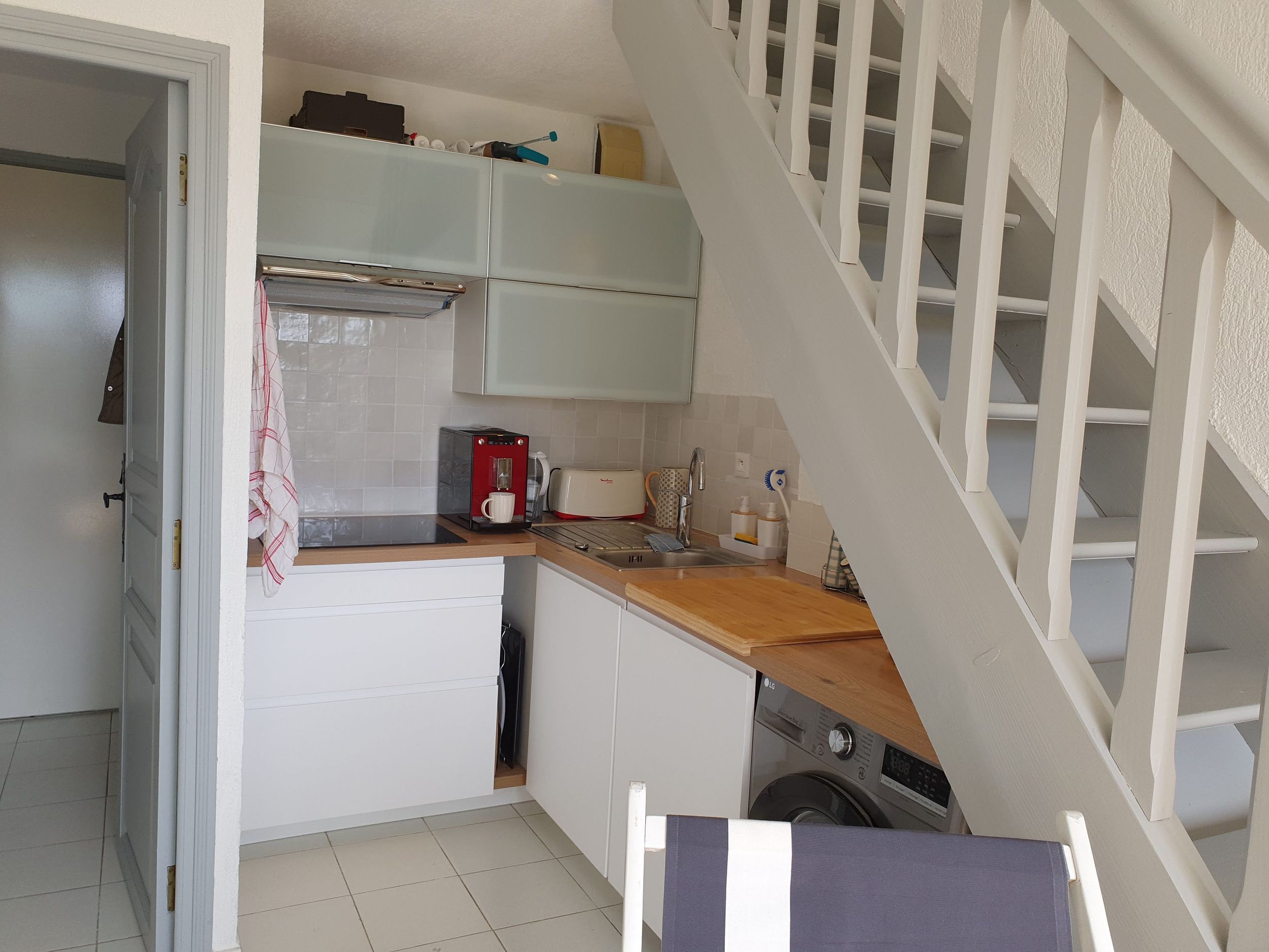 A compact kitchen with a built-in washing machine, a coffee maker, and a toaster.