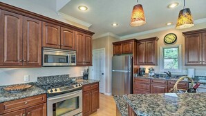A kitchen with wooden cabinets, stainless steel appliances, granite countertops, and pendant lighting. - Bull Shoals Retreat with Panoramic River Views – A Peaceful Escape Awaits! (Bull Shoals)