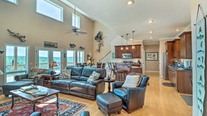 A spacious living room with leather furniture, a dining area, and a kitchen. - Bull Shoals Retreat with Panoramic River Views – A Peaceful Escape Awaits! (Bull Shoals)