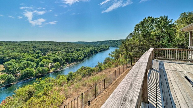 A wooden deck overlooking a river with dense greenery and a clear sky. - Bull Shoals Retreat with Panoramic River Views – A Peaceful Escape Awaits! (Bull Shoals)