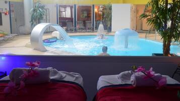 Un espace piscine agrémenté d’un élément décoratif aquatique, de chaises longues et offrant une vue sur la piscine depuis une chambre dotée d’un lit et d’une plante.