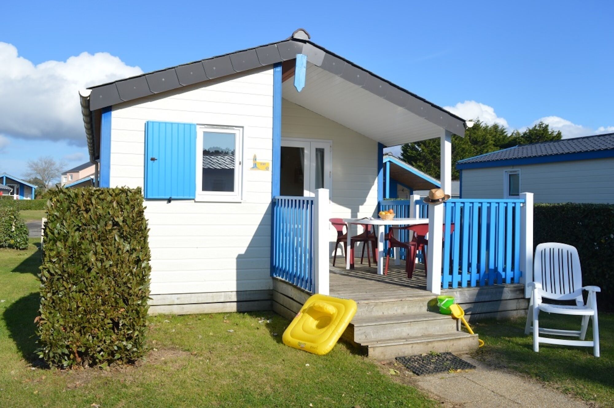 A small, single-story house with a porch, a blue door, and a white exterior.
