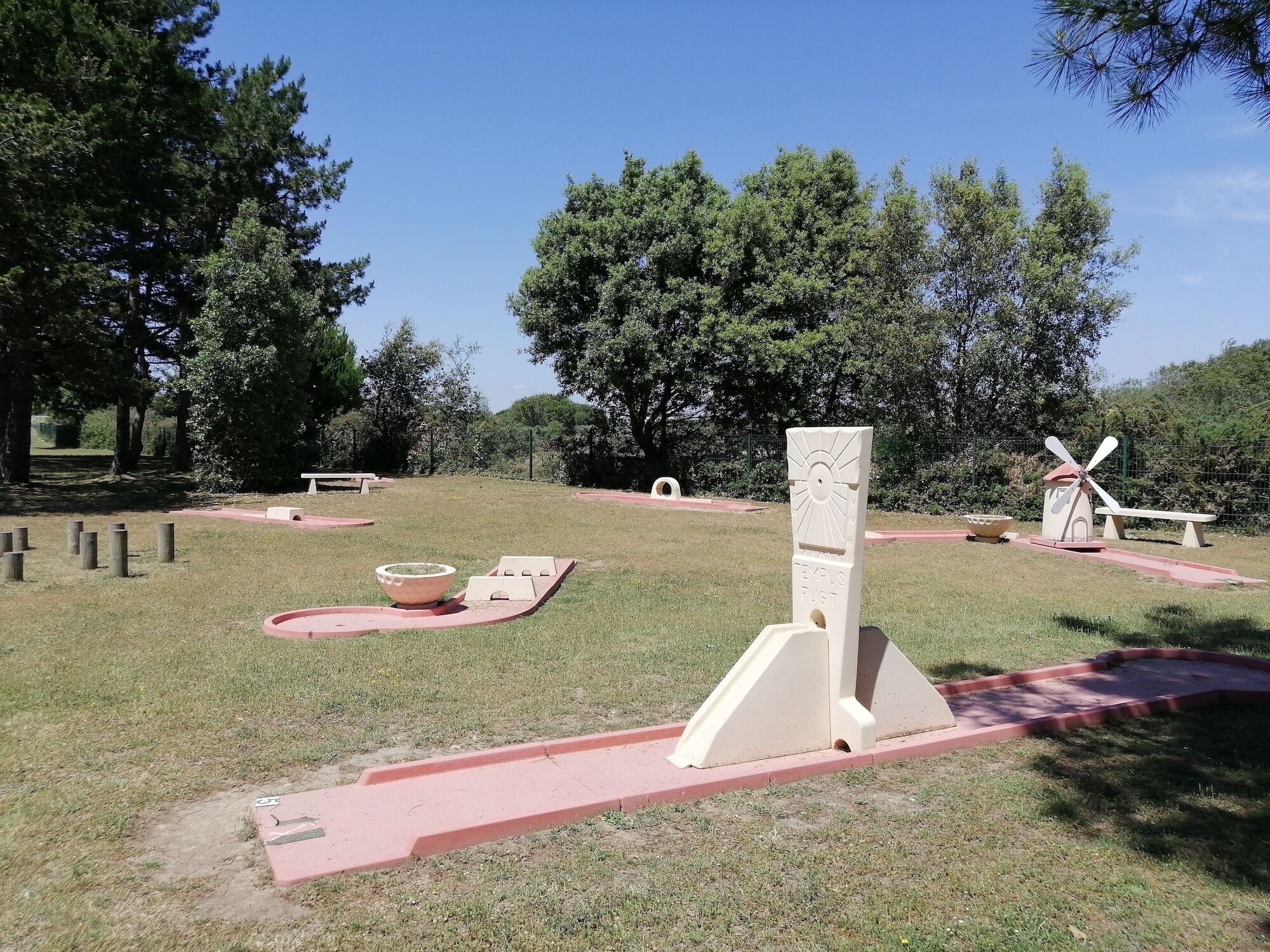 Un parque con un molino, un reloj de sol y un banco de piedra.