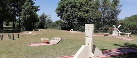 Un parque con un molino, un reloj de sol y un banco de piedra.
