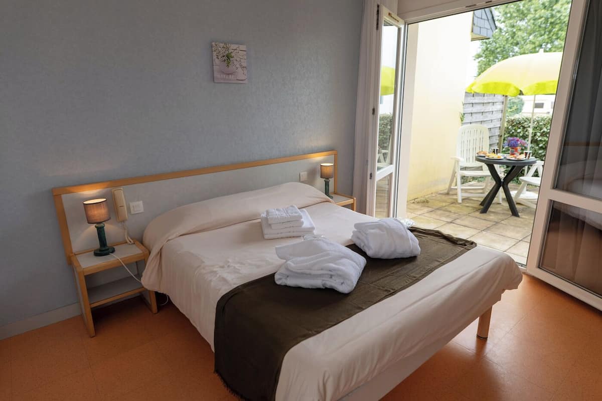 Een hotelkamer met een bed, bedlampen, een klein tafeltje en uitzicht op het buitengebied.