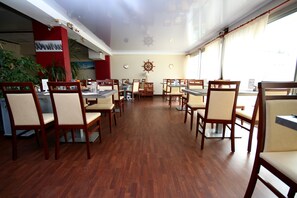 Un restaurante con suelo de madera, sillas color beige y decoración náutica en la pared.