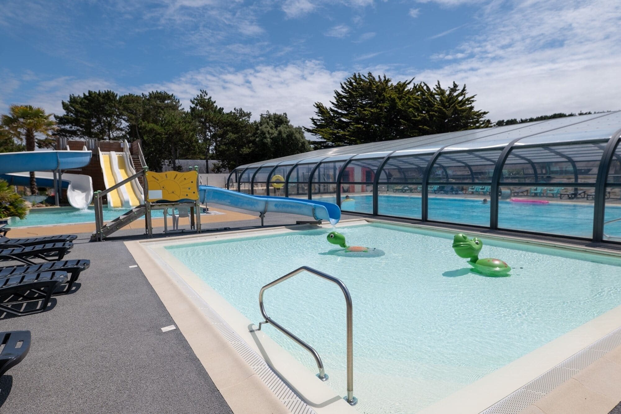 A swimming pool with slides and a covered area.