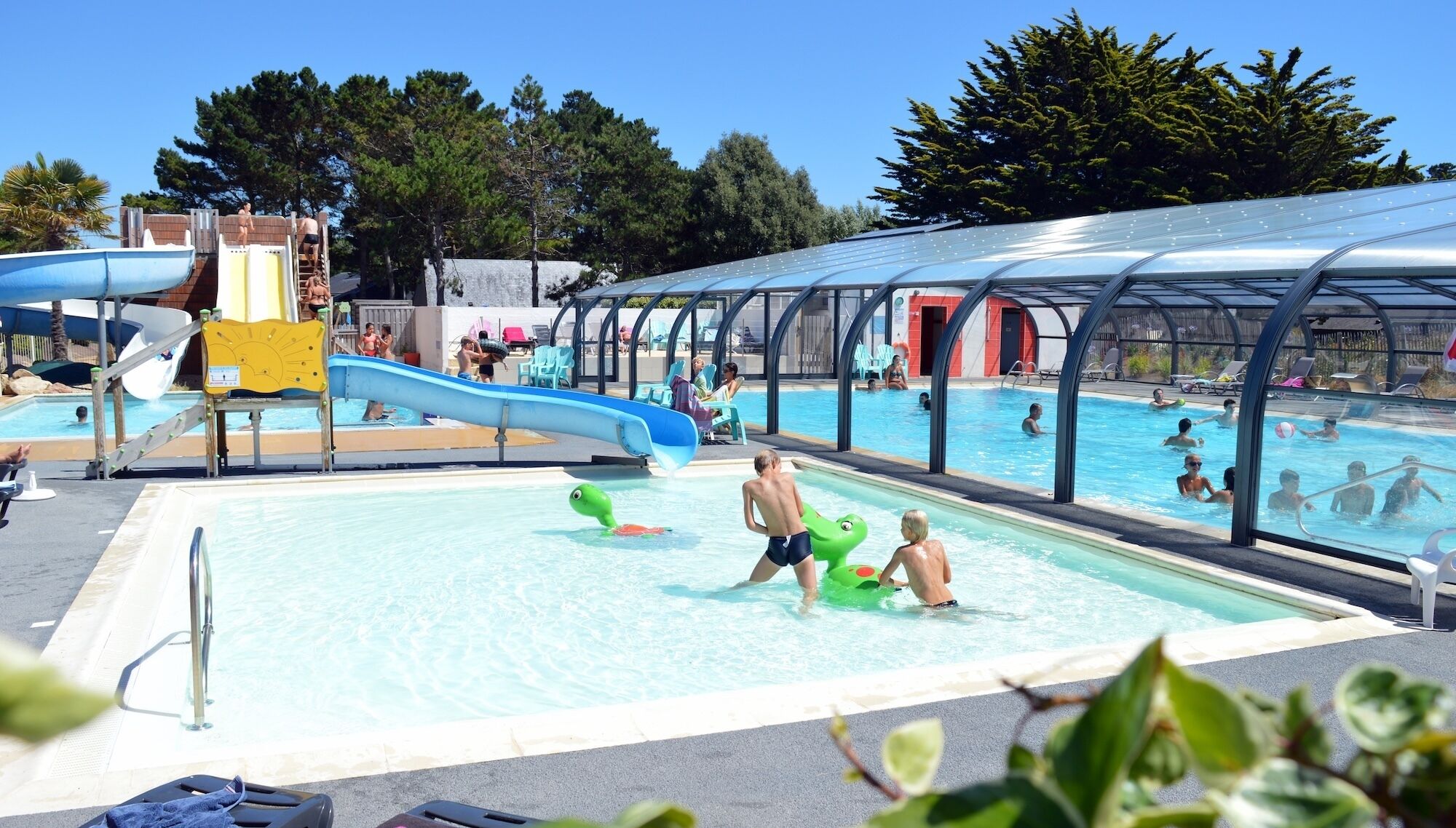 A swimming pool with a slide, a covered area, and a separate pool for children.